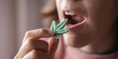 A Woman On Cannabis With The Munchies Eating A Weed-leafed Shaped Gummy Snack.
